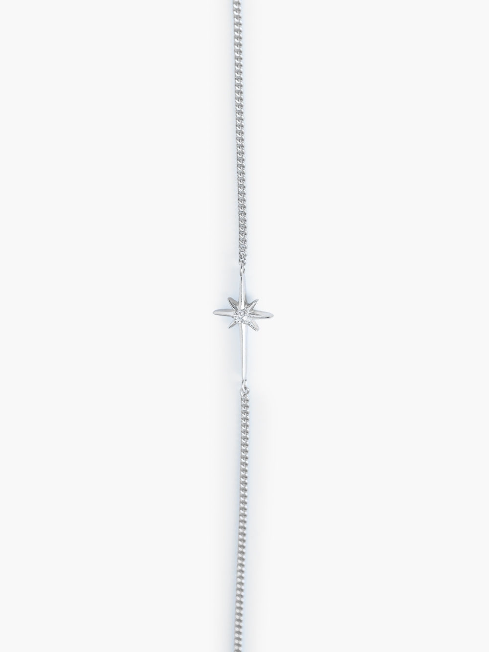 Close-up of the star-cross charm showing the 2mm cubic zirconia center of the silver Adoring Star Bracelet, designed by Rizen Jewelry. 