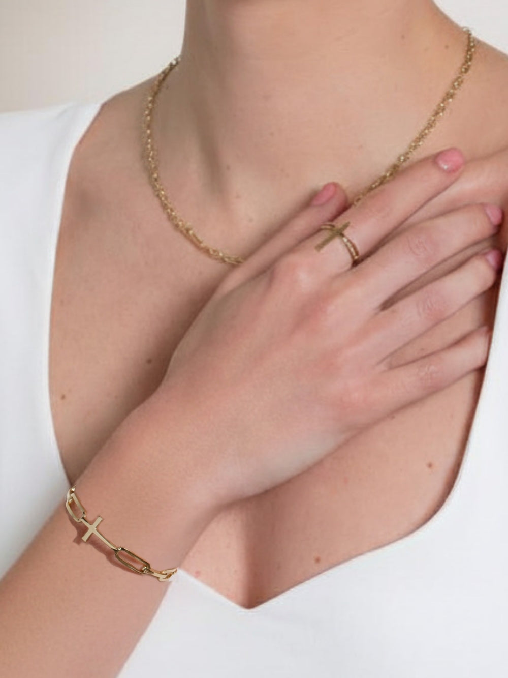 Woman's Christian jewelry model wearing the bold yet sleek cross cuff bangle featuring striking links seamlessly transitioning into the classic Rizen Cross in heavy 18k gold plating. 