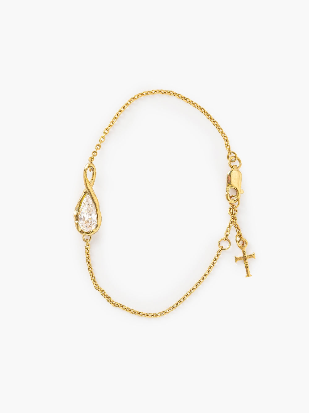 Rizen Jewelry's Solace Teardrop Bracelet is set on a delicate gold cable chain bracelet featuring a teardrop-shaped pendant with a clear faceted gemstone, a small gold cross charm, and a lobster clasp, displayed on a clean white background.