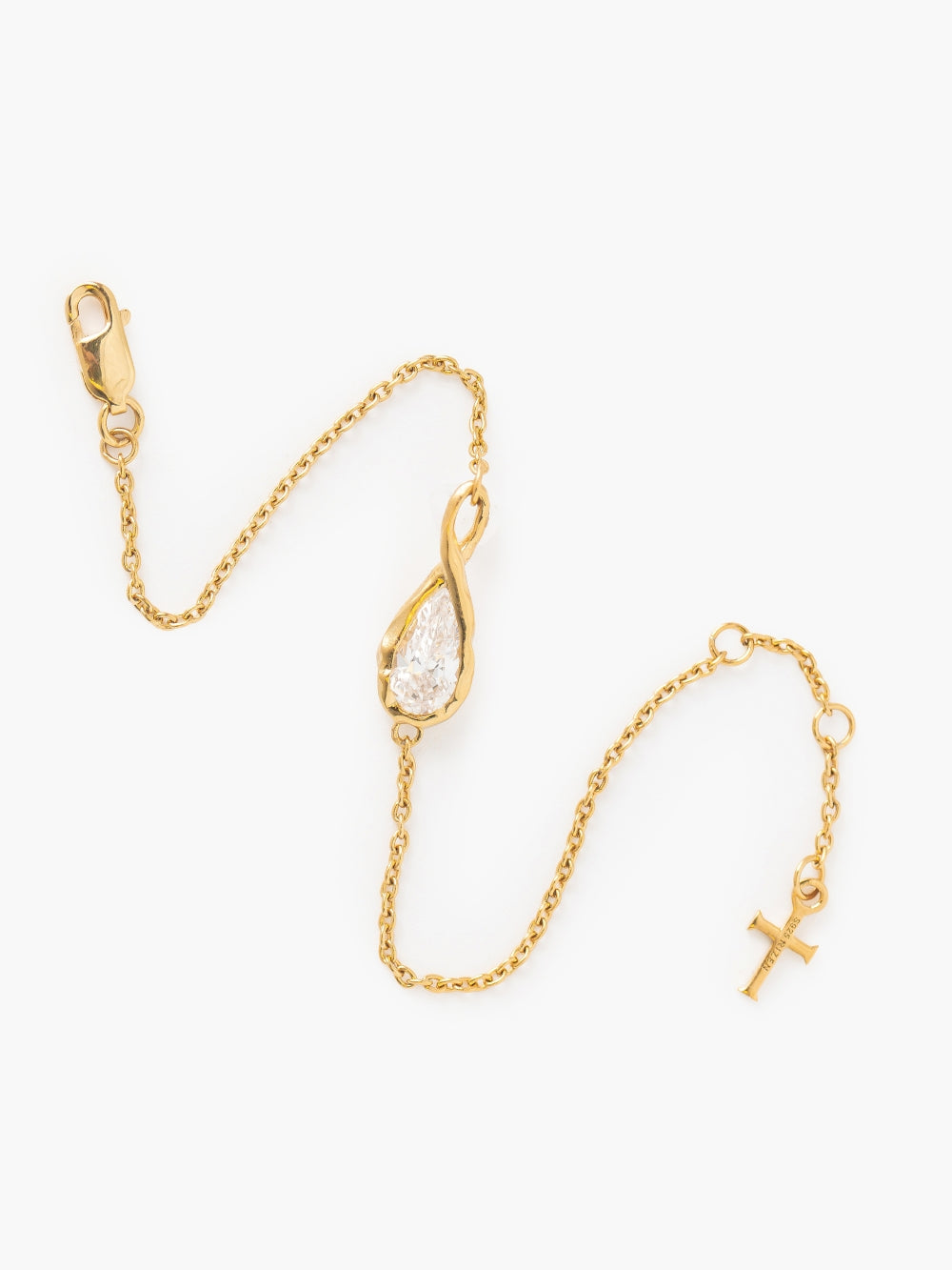 Rizen Jewelry's Solace Teardrop Bracelet is a delicate gold chain bracelet featuring a teardrop-shaped simulated diamond in a gold bezel setting, that forms an infinity symbol. It has a lobster clasp and is adjustable to 3 different lengths and has a dainty cross tag at the end.  Featured on a plain white background.