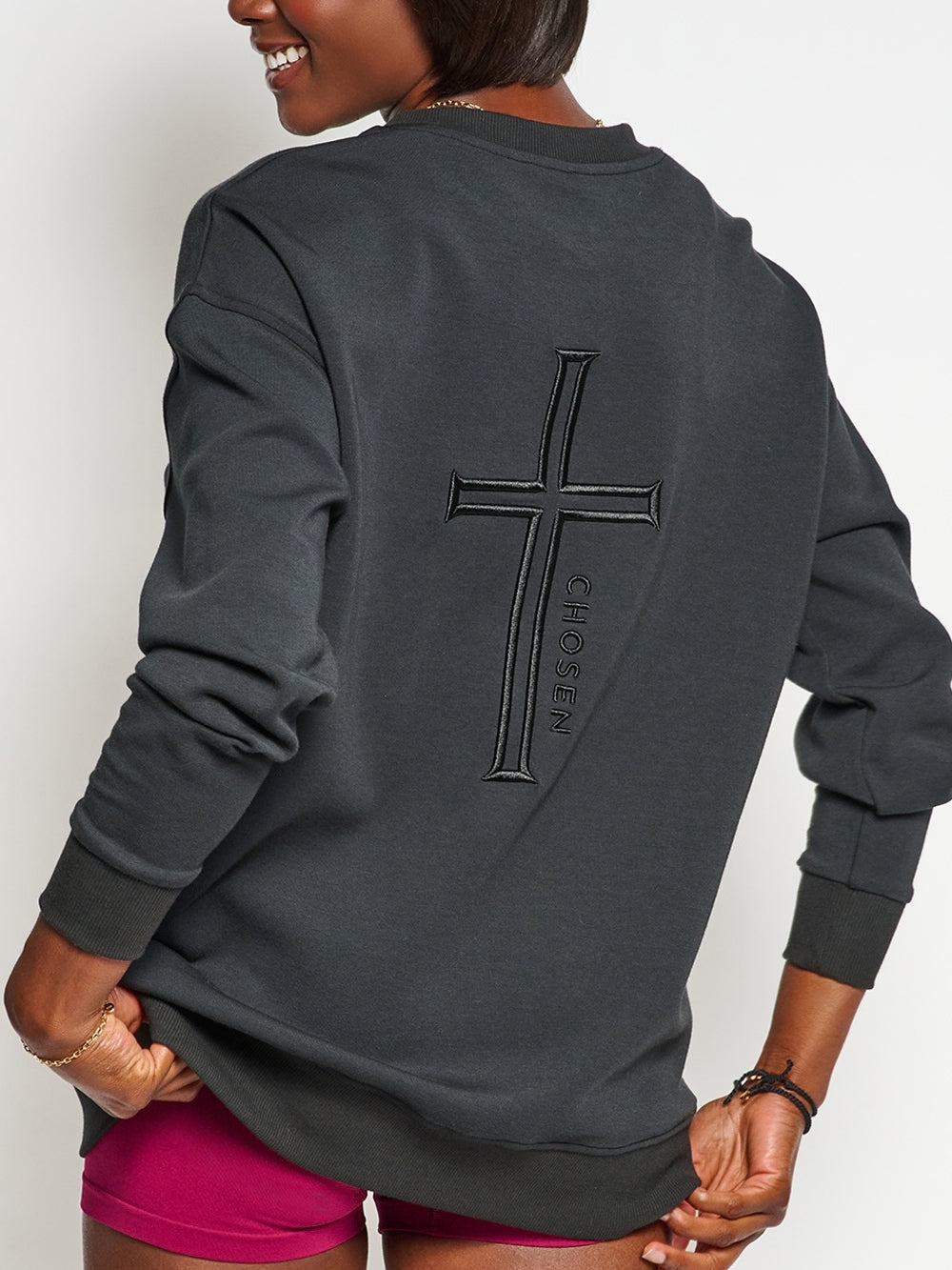 Christian female sweatshirt model wearing Chosen cross sweatshirt styled with shorts.