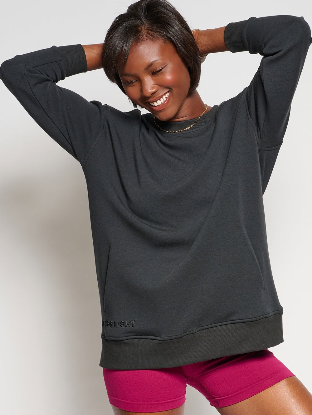 Christian female sweatshirt model wearing  Chosen crew neck sweatshirt with BE THE LIGHT embroidery, cross accent, and discreet front pockets