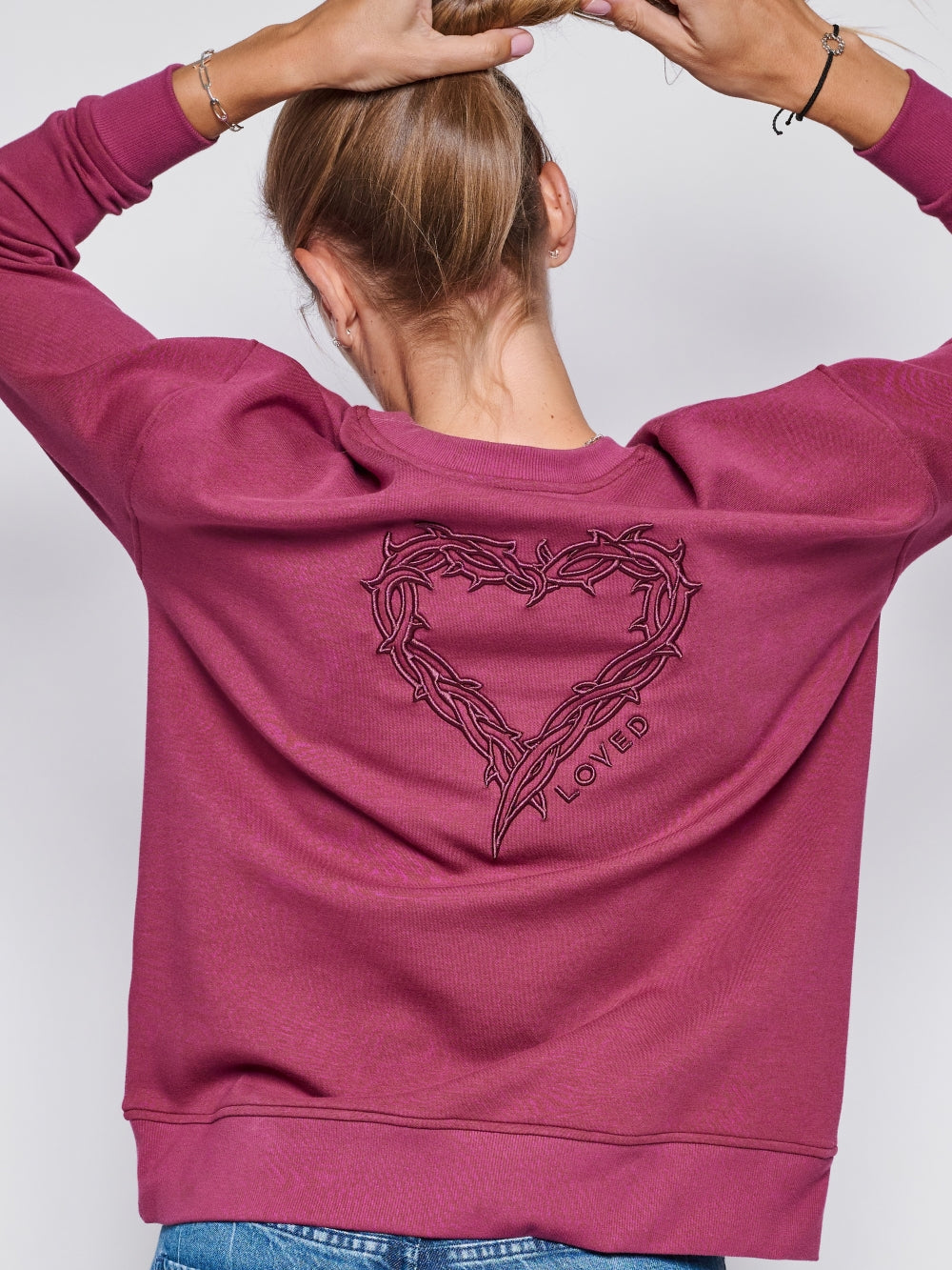 Christian female sweatshirt model wearing Loved John 3:16 sweatshirt styled with blue jeans.
