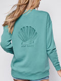 Faith-based female model wearing Stay Salty scallop shell sweatshirt styled with jean shorts
