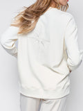 Christian woman's sweatshirt model wearing Joy crewneck sweatshirt with a large embroidered star styled with lounge wear.