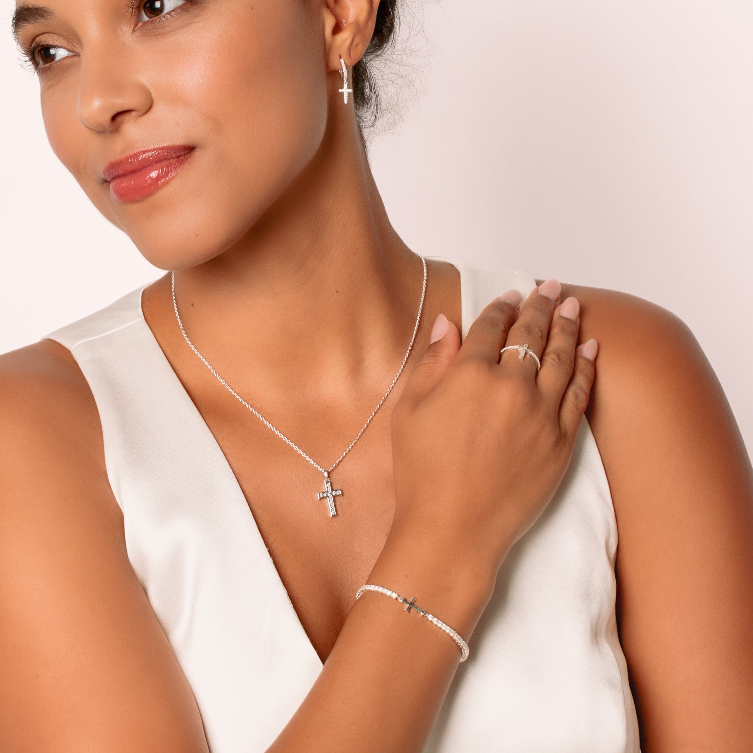 A christian woman jewelry model  wearing the silver luminous cross jewelry from the Calvary Collection by Rizen Jewelry.