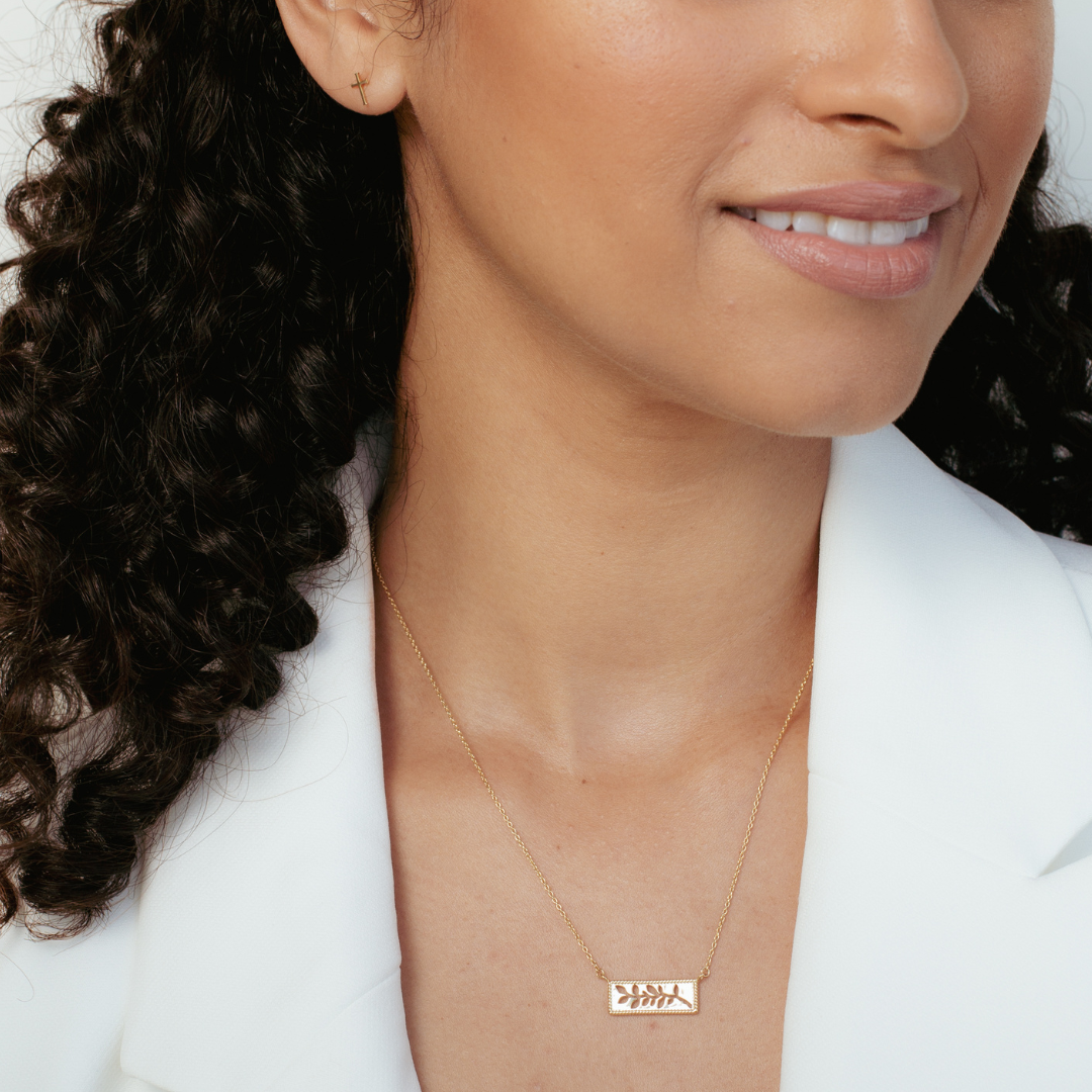 Close up of christian woman wearing 18k gold vermeil olive branch necklace and mini cross stud earrings from the Rooted Collection by Rizen Jewelry. 