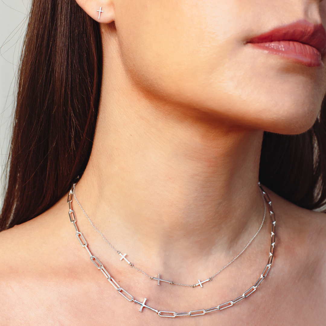 Close up of christian woman neck wearing sterling silver calvary cross station necklace and chain breaker cross paperclip necklace from the Calvary Collection by Rizen Jewelry. 
