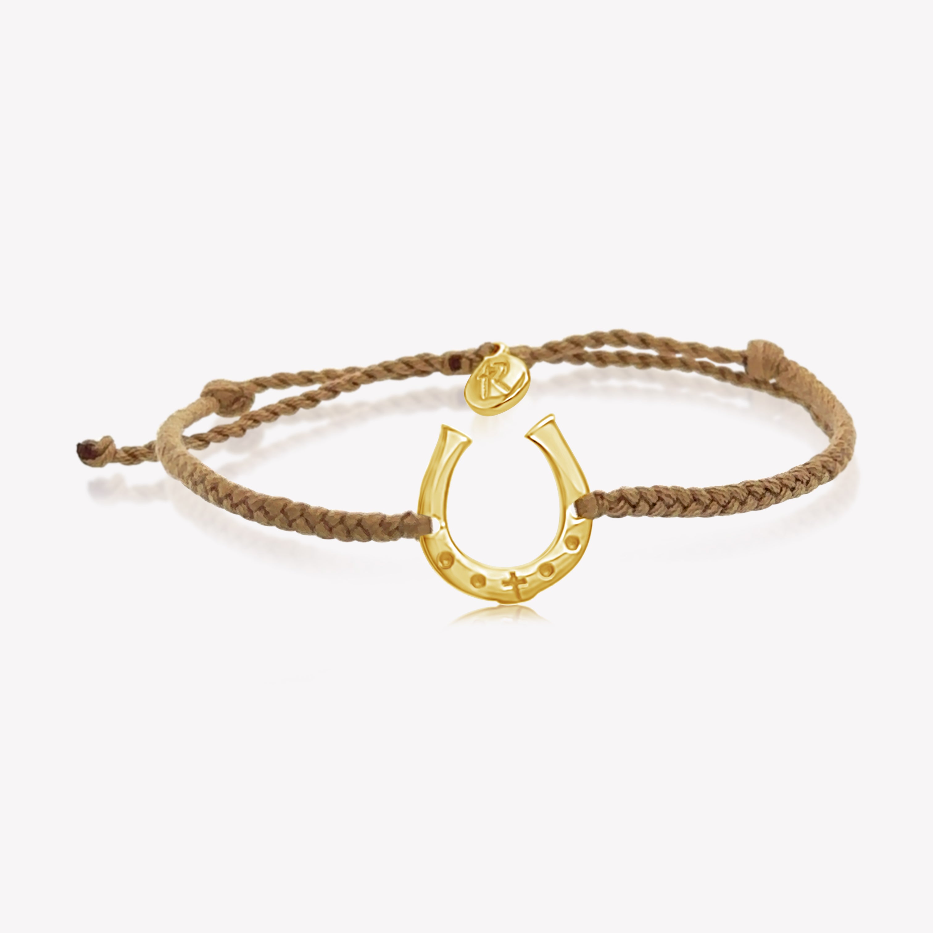 Close up of limited edition khaki cord friendship bracelet featuring a horseshoe pendant in gold from the Made4Ministry Collection by Rizen Jewelry benefitting Big Oak Ranch.
