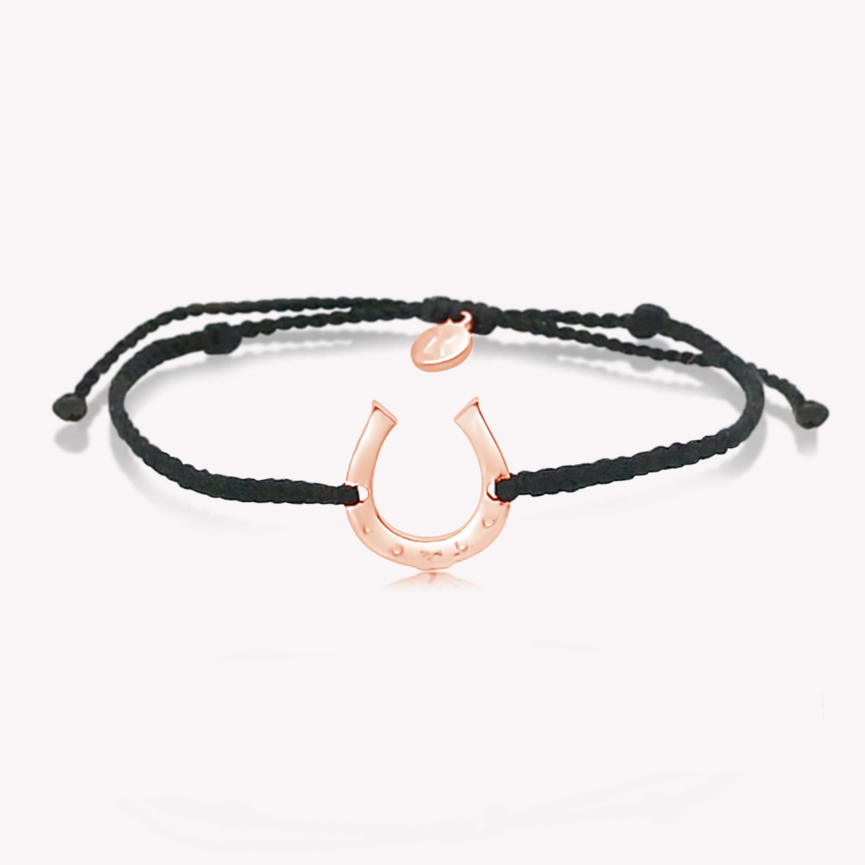 Close up of limited edition black cord friendship bracelet featuring a horseshoe pendant in rose gold from the Made4Ministry Collection by Rizen Jewelry benefitting Big Oak Ranch.