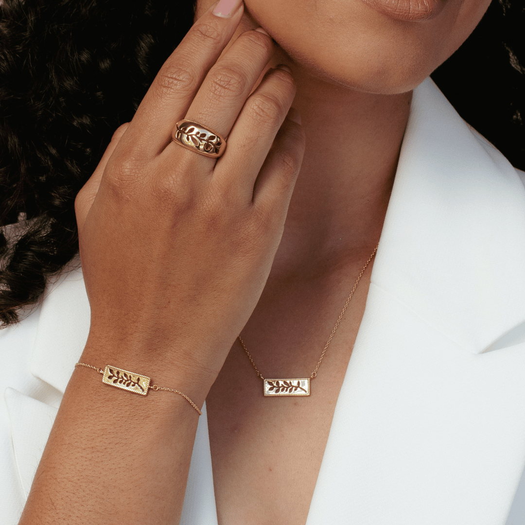 Close up of christian model wearing the 18k gold vermeil Olive Branch Bracelet, Necklace and Ring from the Rooted Collection by Rizen Jewelry. 