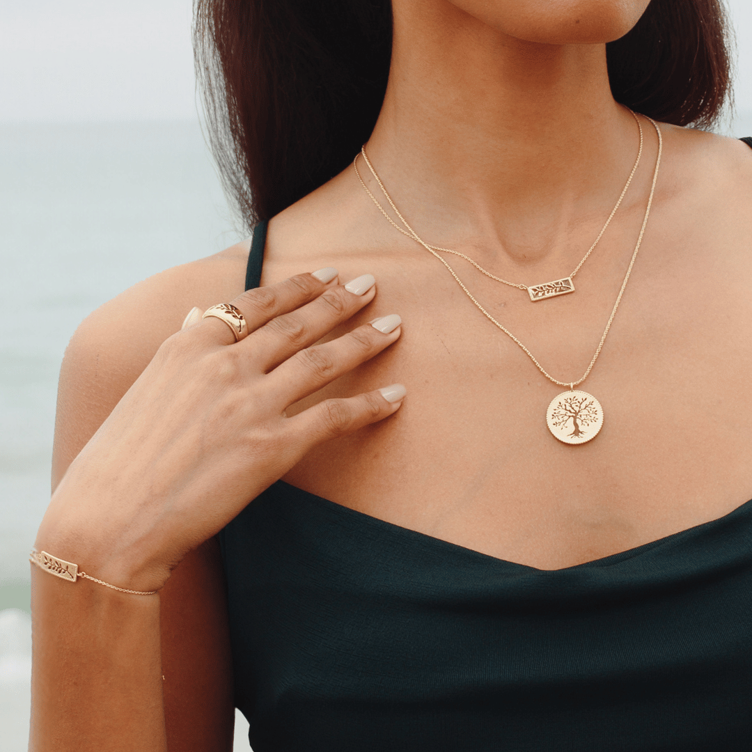 Christian woman wearing the 18k gold vermeil Rooted Collection featuring the Olive Tree Necklace, Olive Branch Ring, Bracelet and Necklace by Rizen Jewelry. 