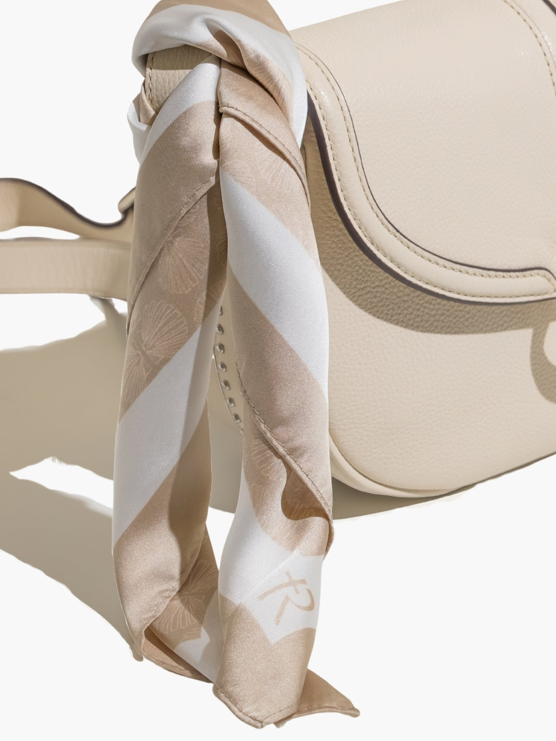 Beige purse with the  Rizen scarf tied on as an accessory. 