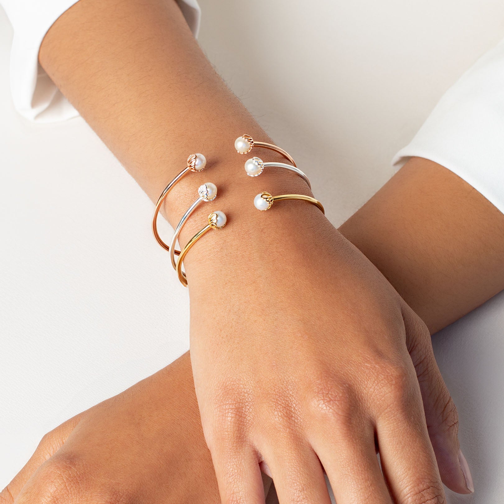 Close up of a christian woman wearing the 18k gold, rose gold vermeil, and sterling silver Shell Encased Pearl Bangle Bracelets from the Becoming Collection by Rizen Jewelry.