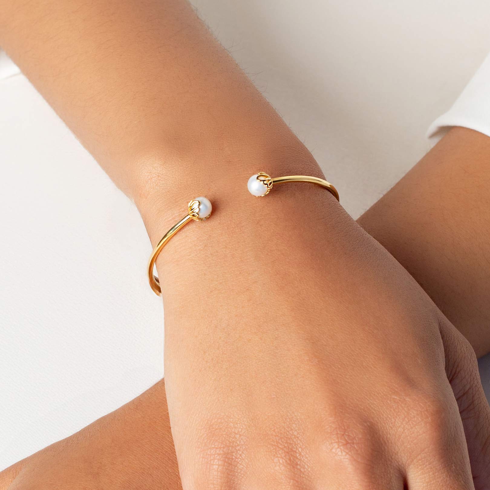 Close up of a christian woman wearing the 18k gold vermeil Shell Encased Pearl Bangle Bracelet from the Becoming Collection by Rizen Jewelry.