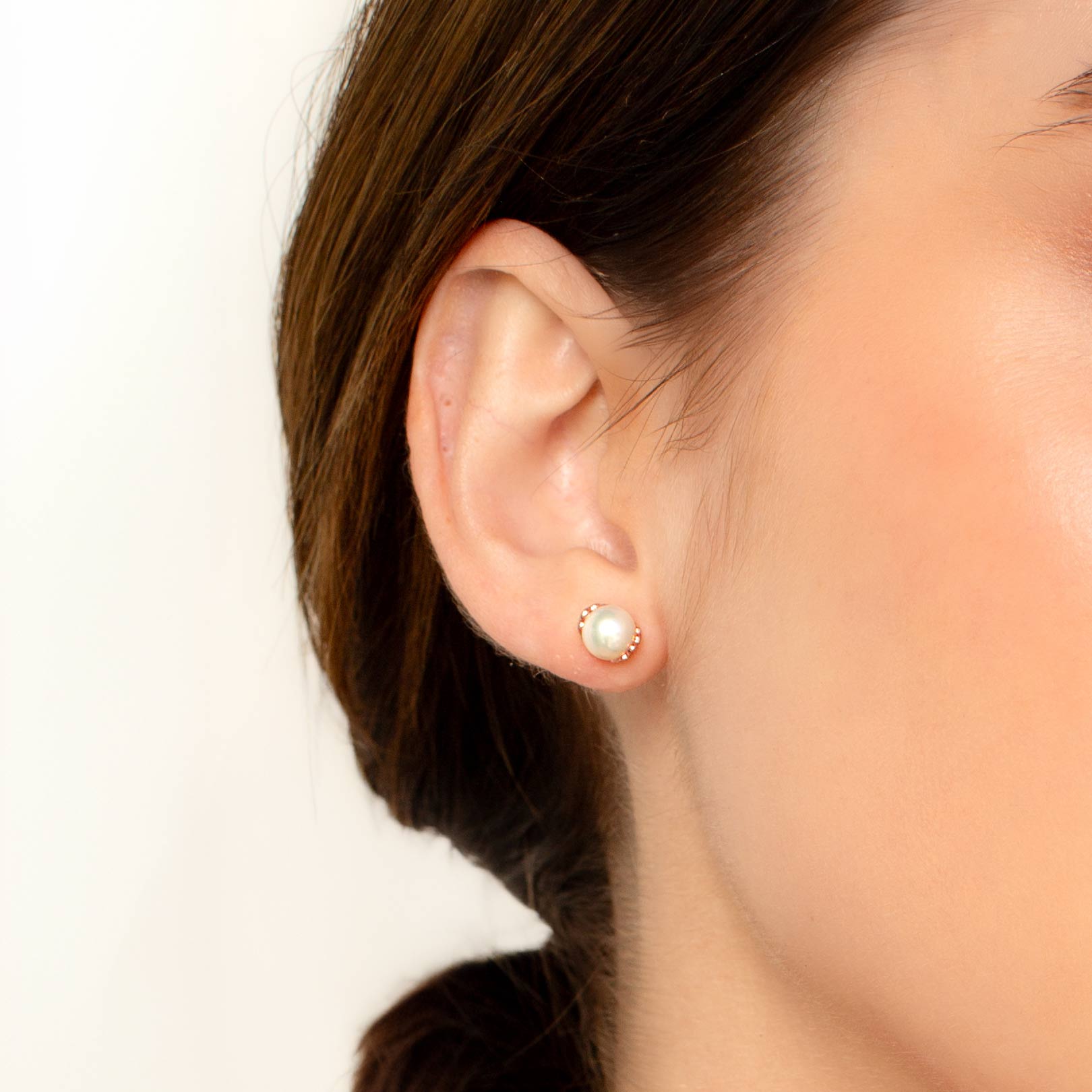 Close up of a christian woman wearing the 18k rose gold vermeil Shell Encased Pearl Earring from the Becoming Collection by Rizen Jewelry.
