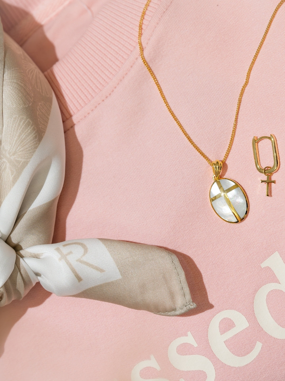 Close-up of the Rizen scarf styled with Mother Pearl Cross necklace and Chain Breaker hoop earring on blessed sweatshirt 