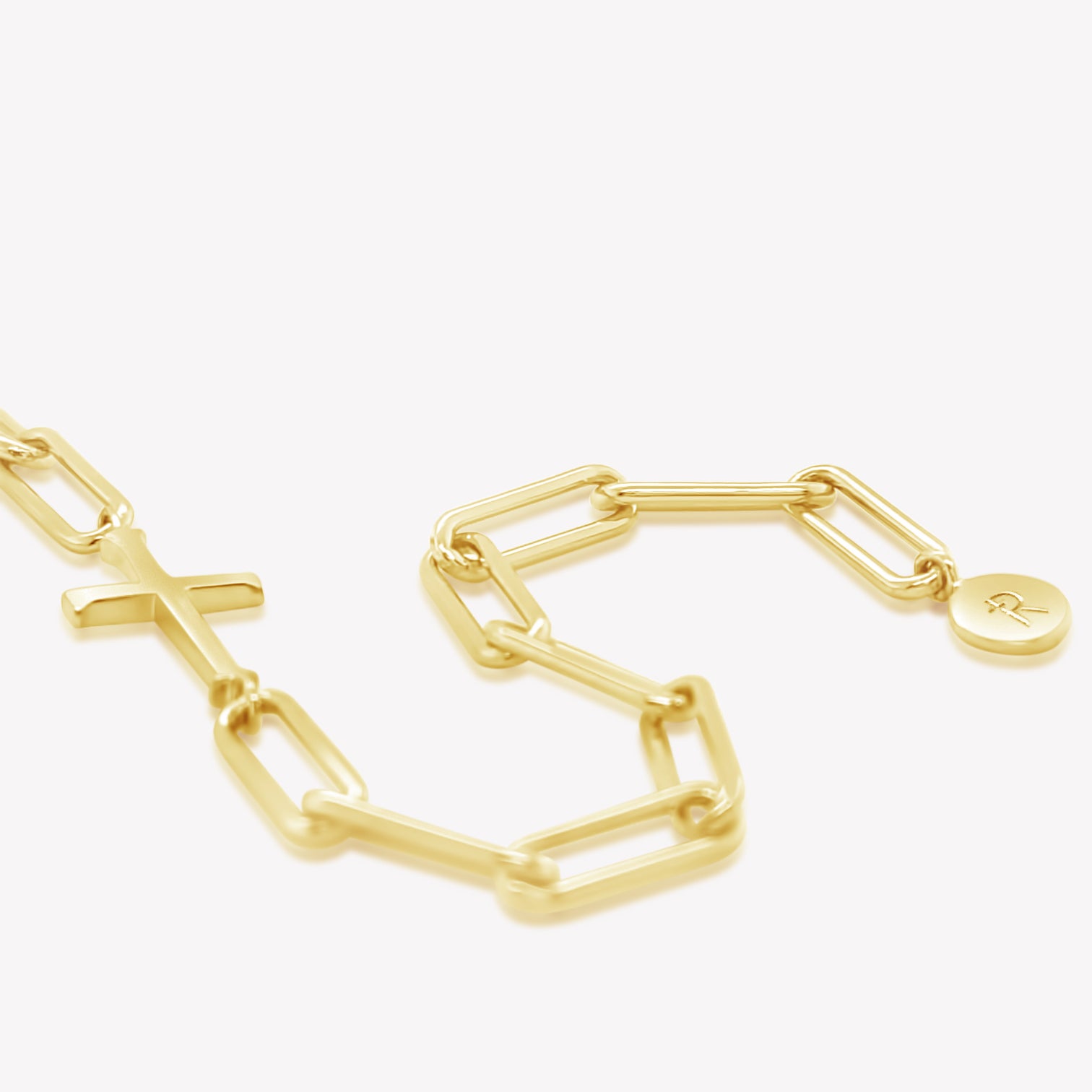 Rizen Jewelry Chain Breaker bracelet in 18kt yellow gold.  Elegant Cross Pendant breaks up the contemporary paper clip link chain with circular Rizen tag on last link of chain.