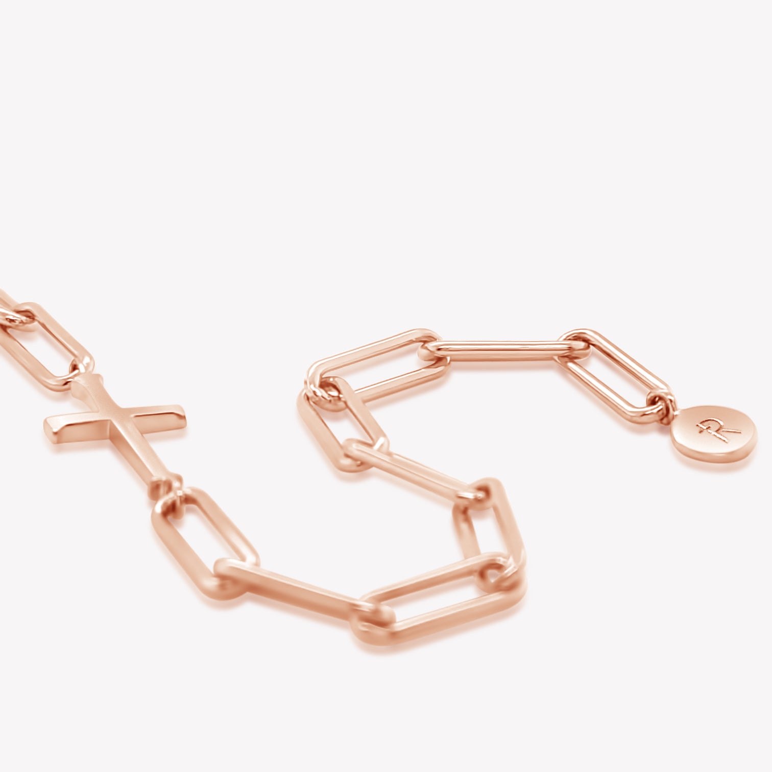 Rizen Jewelry Chain Breaker bracelet in 18kt rose gold.  Elegant Cross Pendant breaks up the contemporary paper clip link chain with circular Rizen tag on last link of chain.