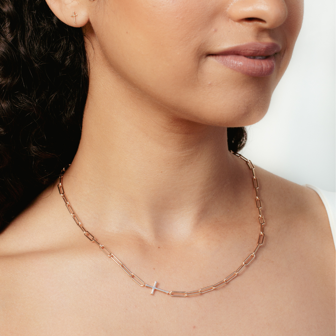 Woman wearing Rizen Jewelry Chain Breaker necklace in 18kt rose gold. Elegant Cross Pendant breaks up the paper clip link chain 