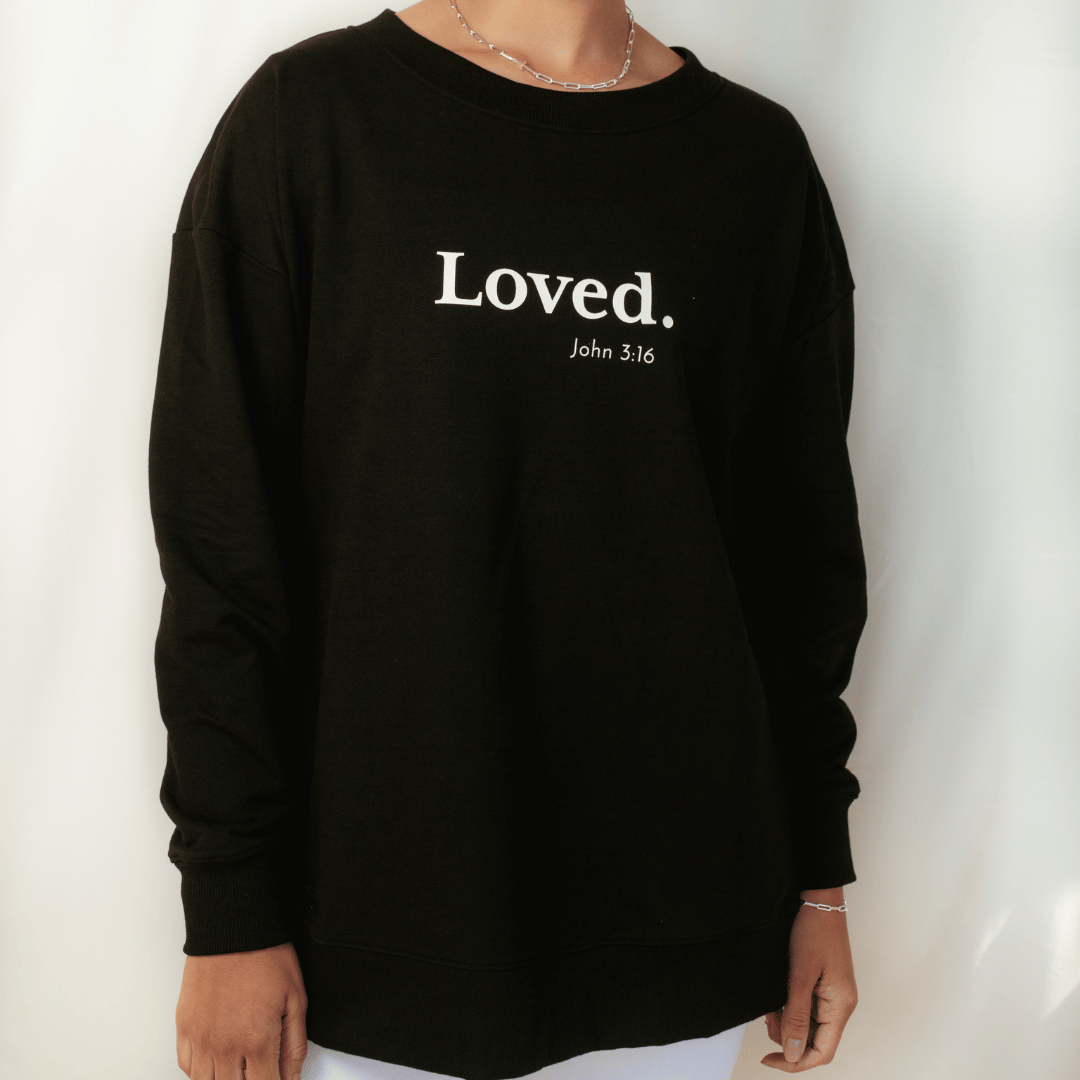Christian woman wearing the black " Loved. John 3:16" Peruvian cotton crew sweatshirt from the Be The Light Collection by Rizen Jewelry.