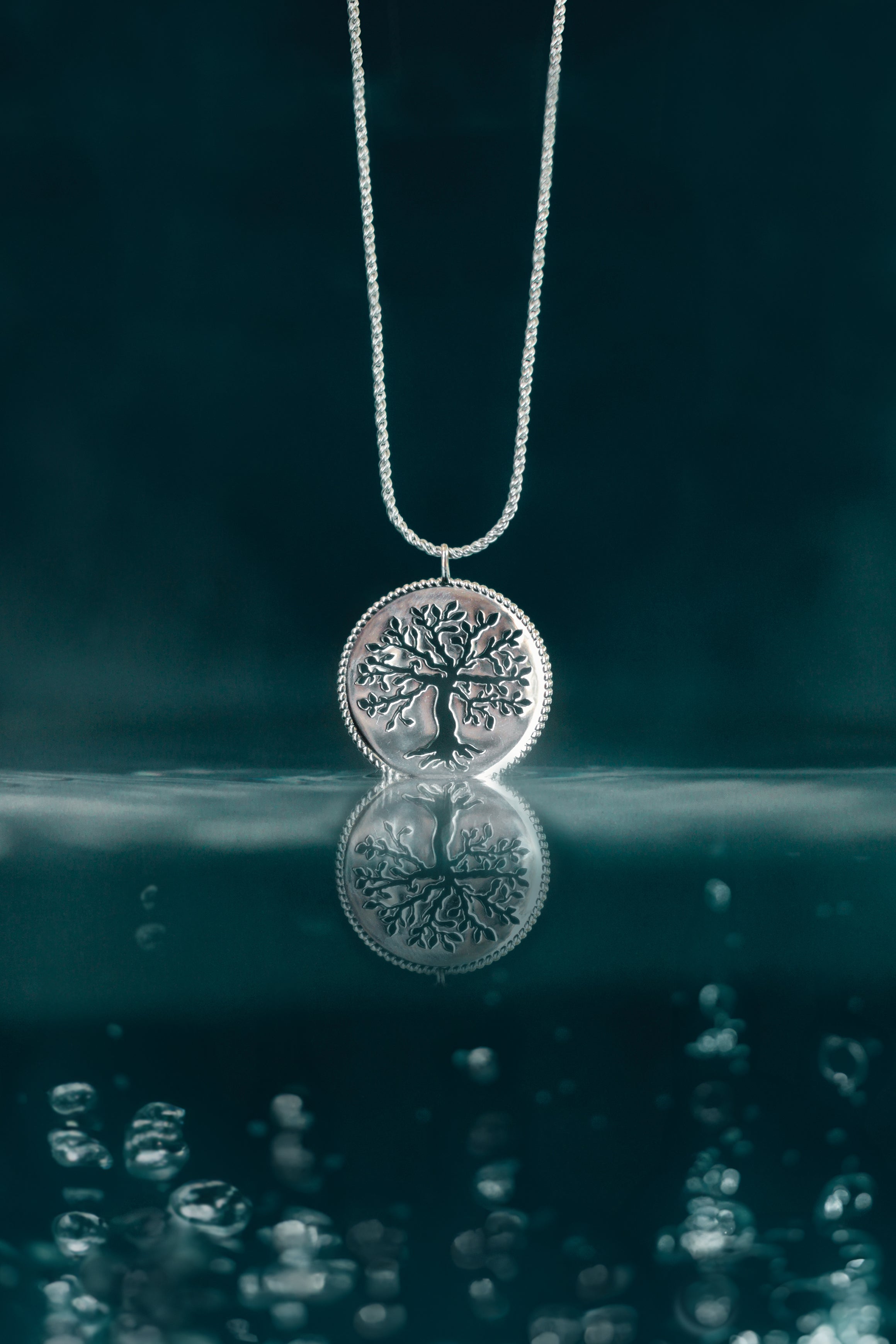 Rizen Jewelry sterling silver Rooted Olive Tree Necklace dipping into reflective depth colored water