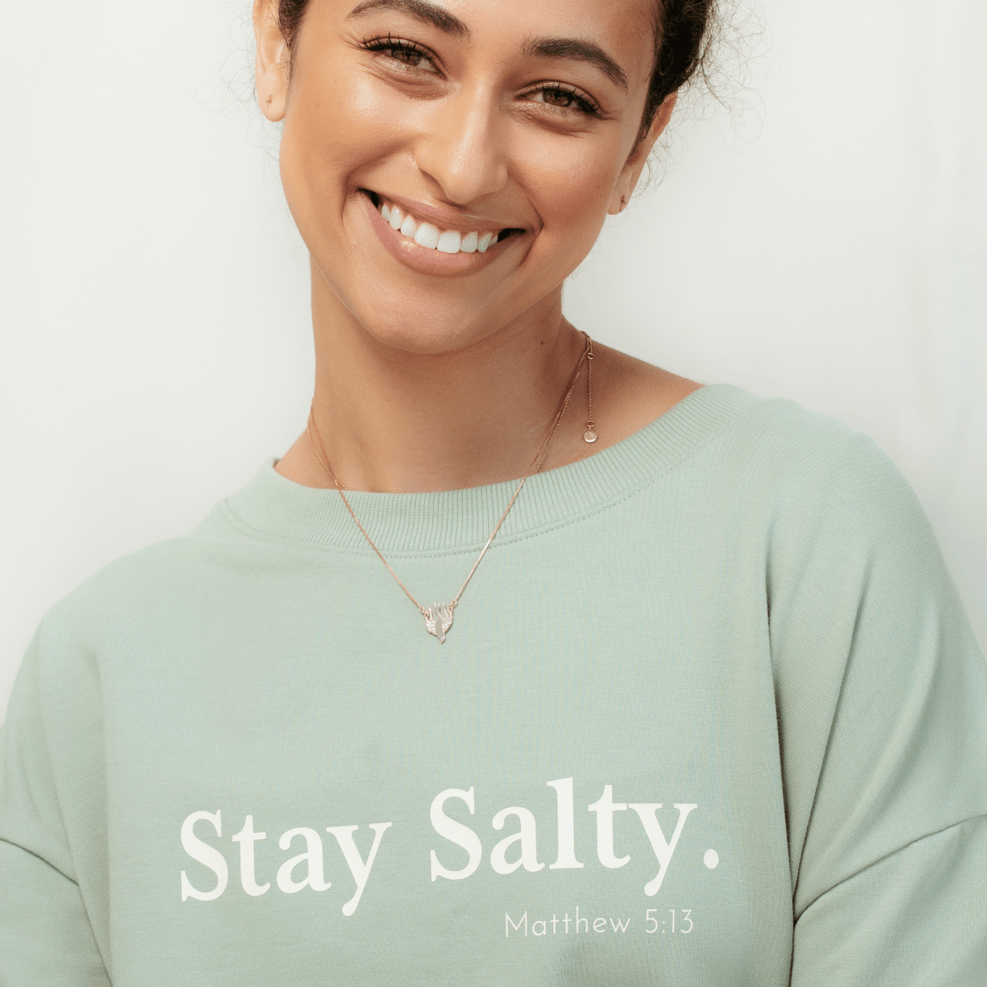 Close up of christian woman wearing the wave green "Stay Salty. Matthew 5:13" Peruvian cotton crew sweatshirt from the Be The Light Collection by Rizen Jewelry.