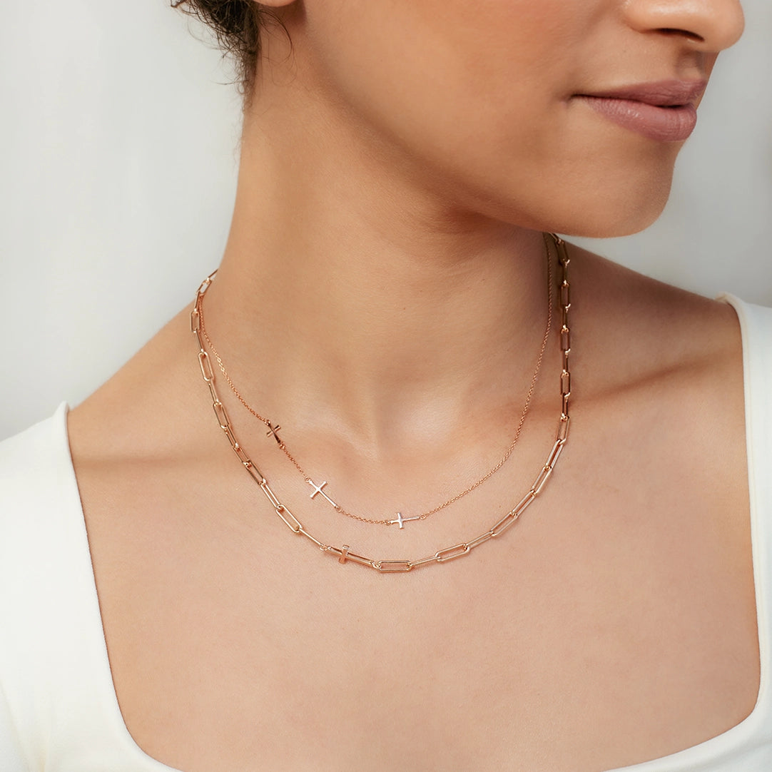Christian woman wearing rose gold triple cross Calvary Necklace and Chain Breaker Cross Necklace from the Calvary Collection by Rizen Jewelry.