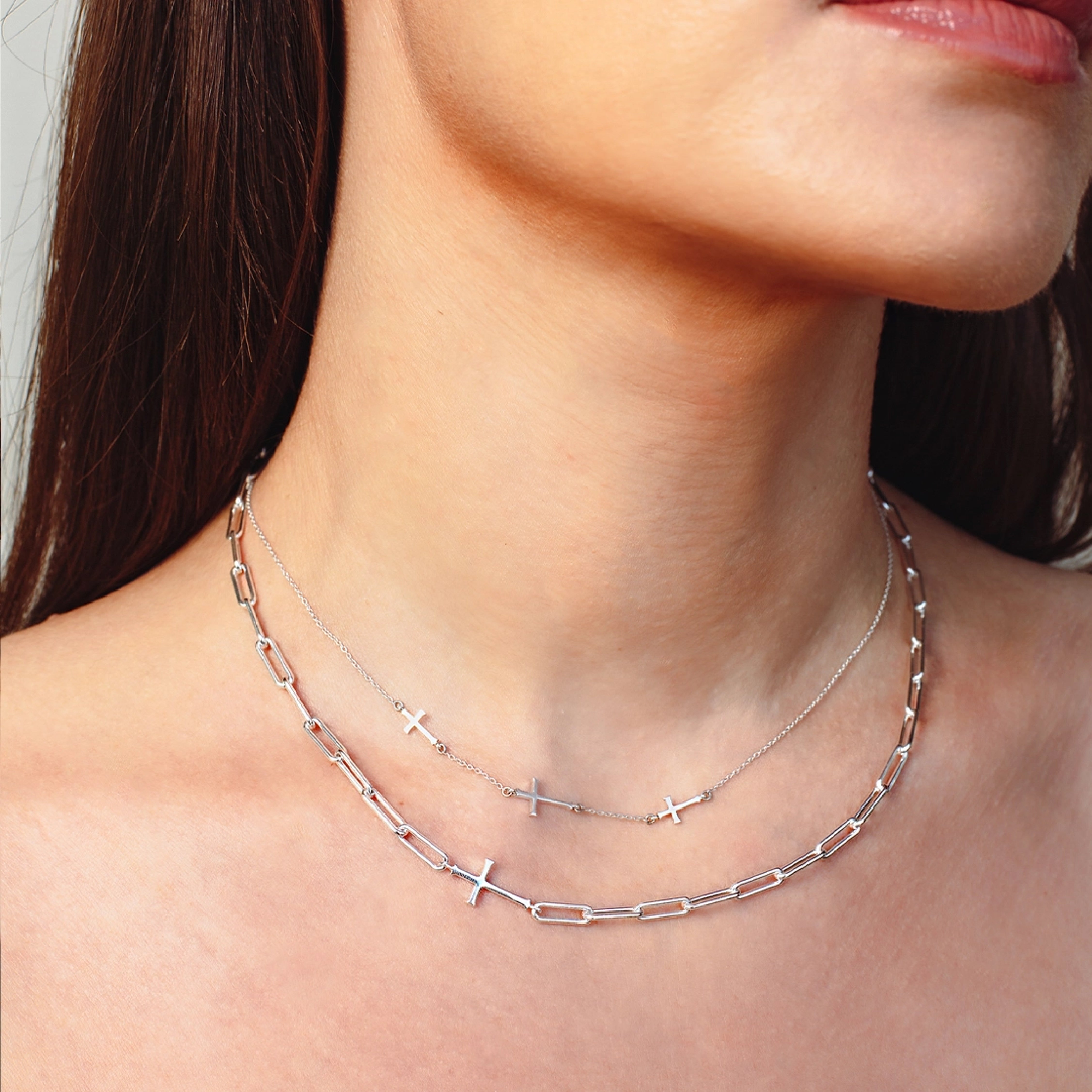 Close up of a christian woman wearing the chain breaker and calvary cross station necklaces in sterling silver from the calvary collection by Rizen Jewelry