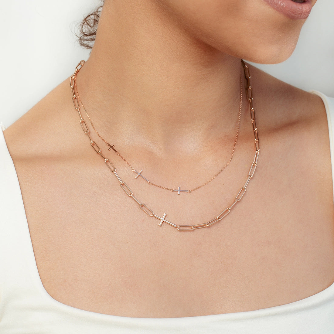 Close up of christian woman wearing the chain breaker and calvary cross necklaces in rose gold vermeil from he calvary collection by Rizen Jewelry. 