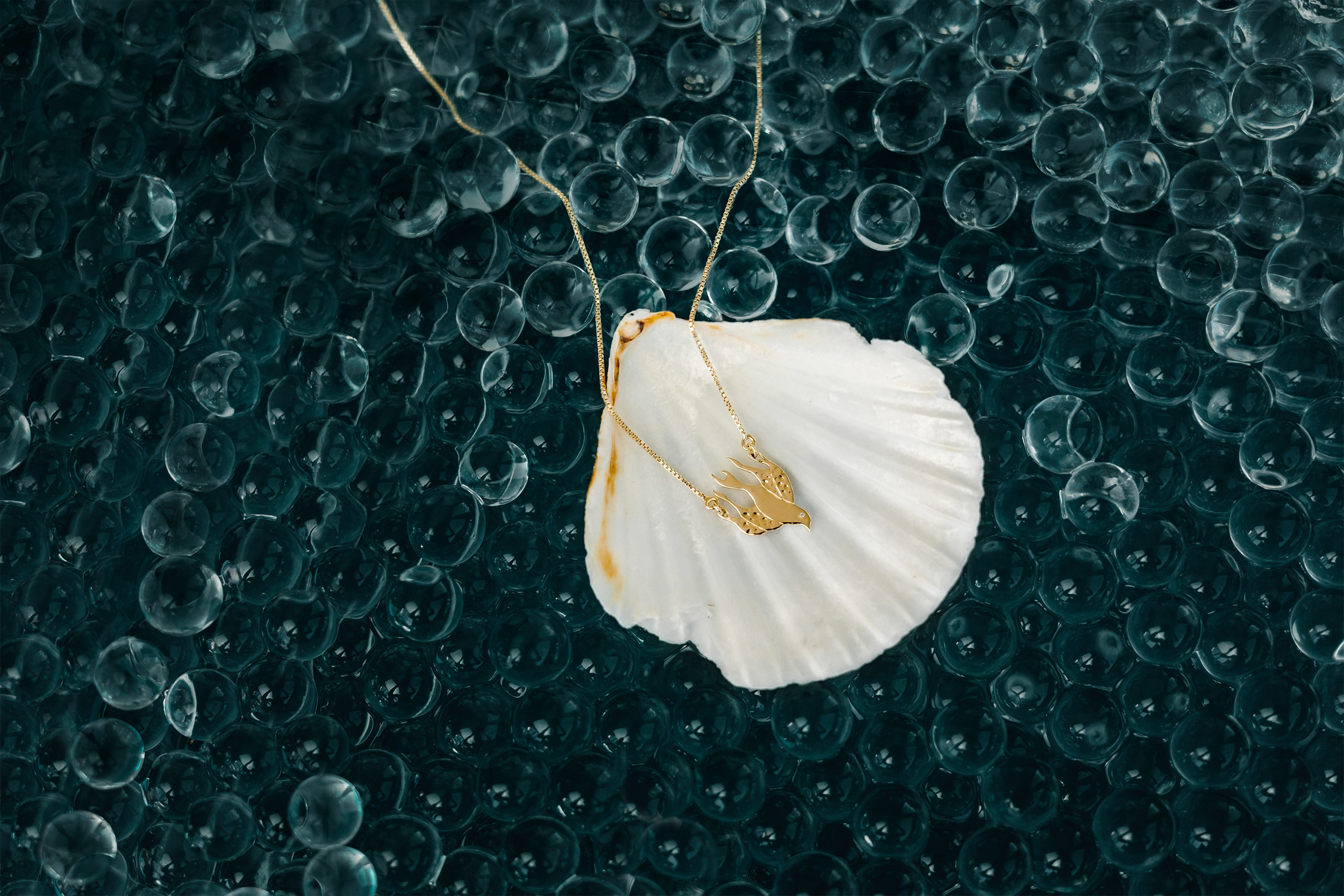 Rizen Jewelry Chispa dove Holy Spirit necklace in 18kt yellow gold vermeil necklace on a scalloped shell 