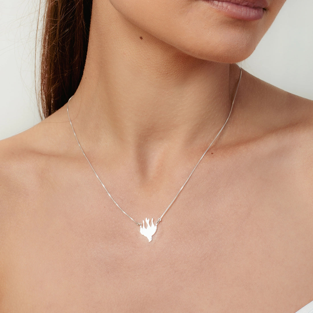Christian woman wearing the Chispa de la Dove Necklace in sterling silver from the Chispa Collection by Rizen Jewelry.