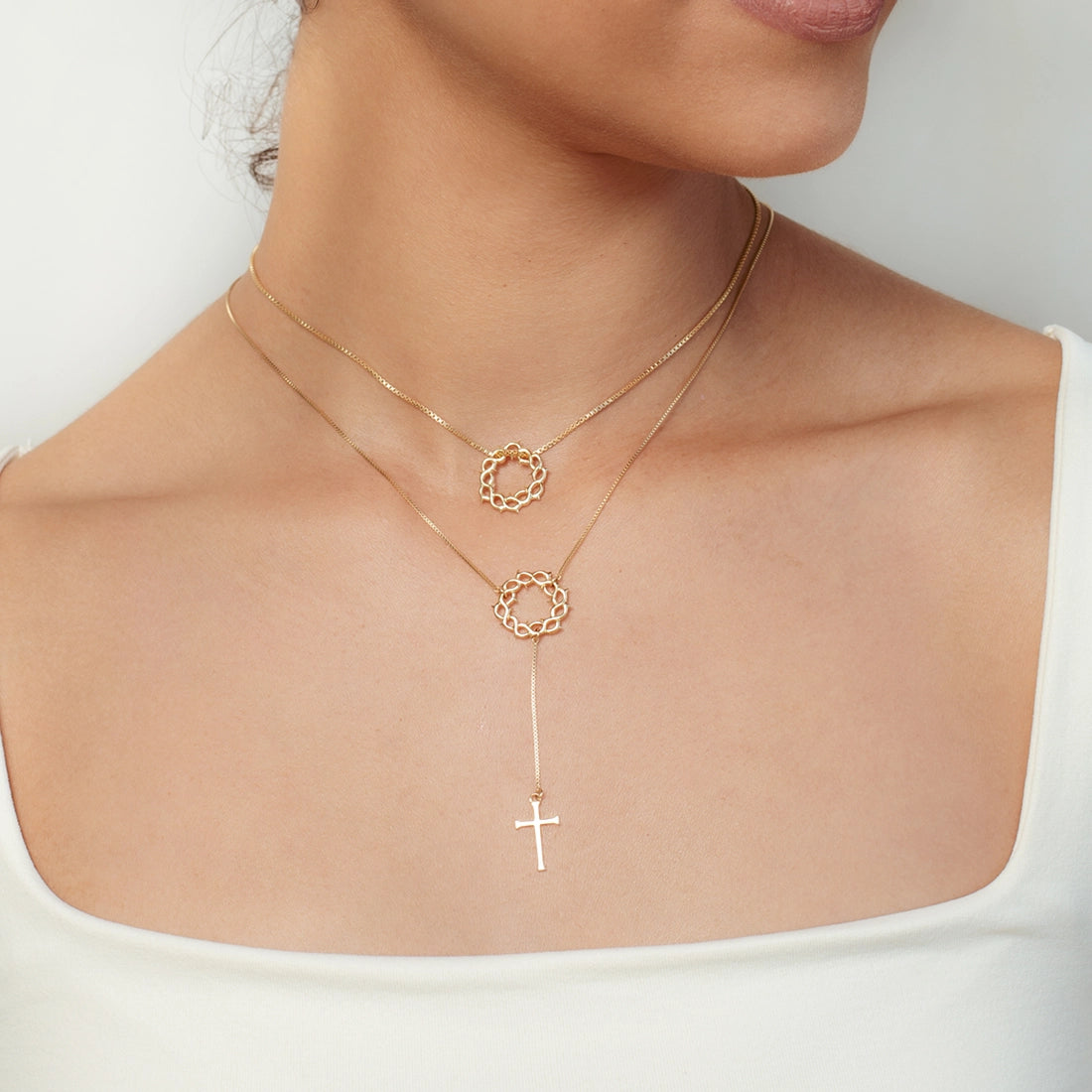 Christian woman wearing 2 Crown of Thorns Necklaces with a cross pendant in 18k gold vermeil from the Insignia Collection by Rizen Jewelry.