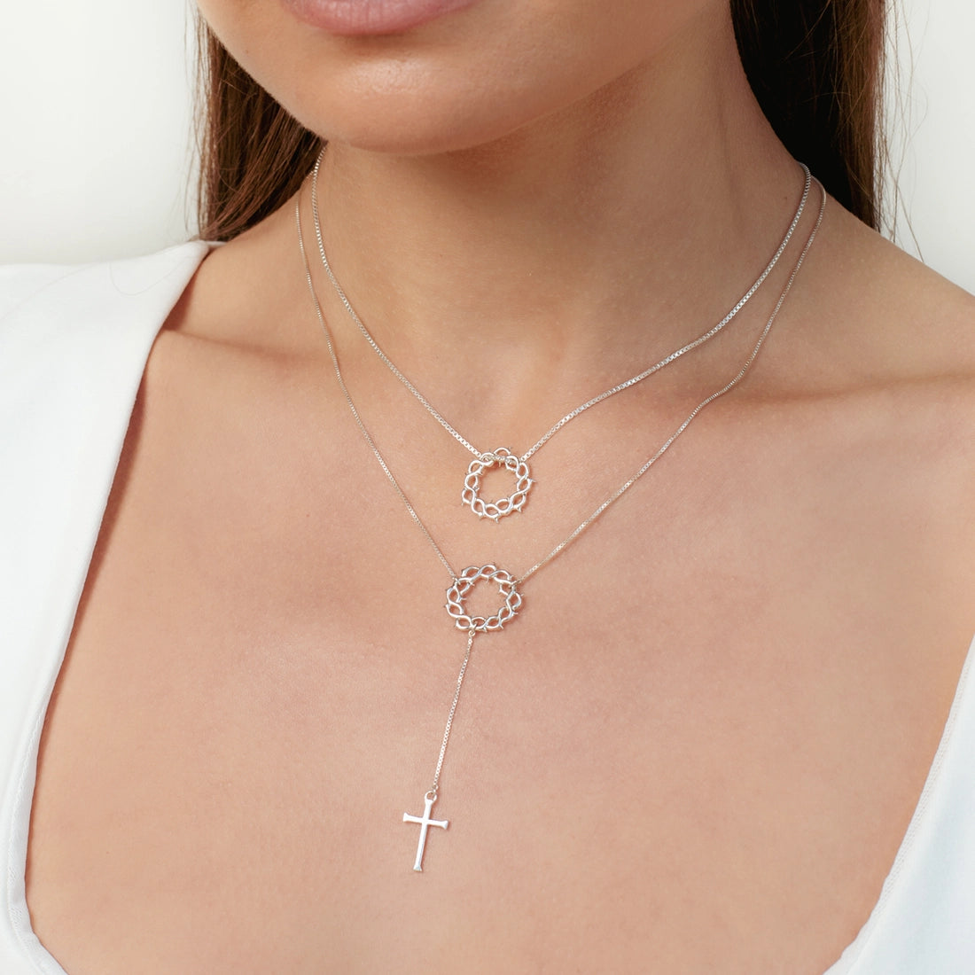 Christian woman wearing 2 silver crown of thorns necklaces one with a cross pendant from the insignia collection by Rizen Jewelry