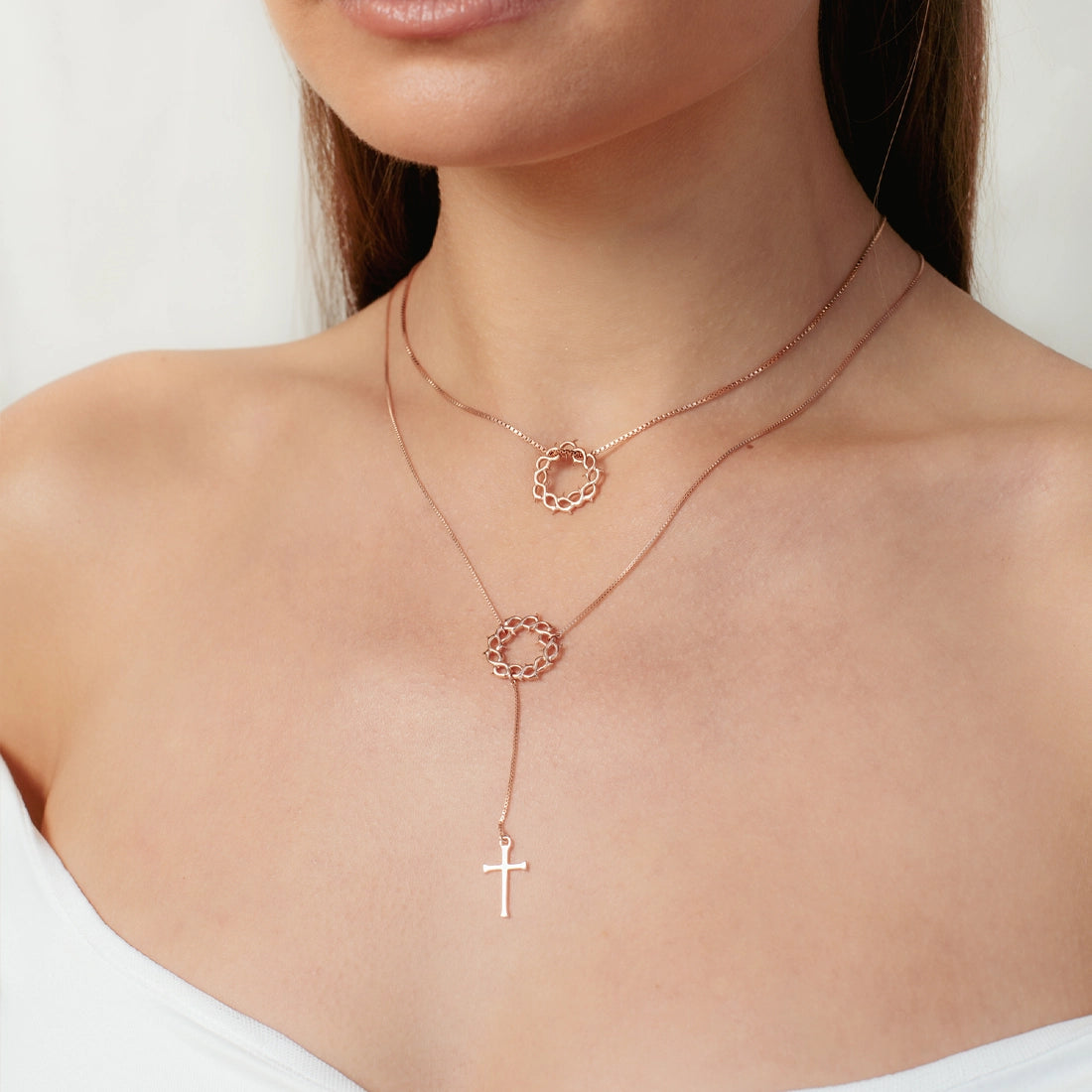 Women's Christian jewelry model is wearing the Crown of Thorns Y Necklace with Cross Pendant in 18k Rose Gold Vermeil alongside the small crown of thorns necklace from the  Insignia collection by Rizen Jewelry. Inspirational gift for any occasion.