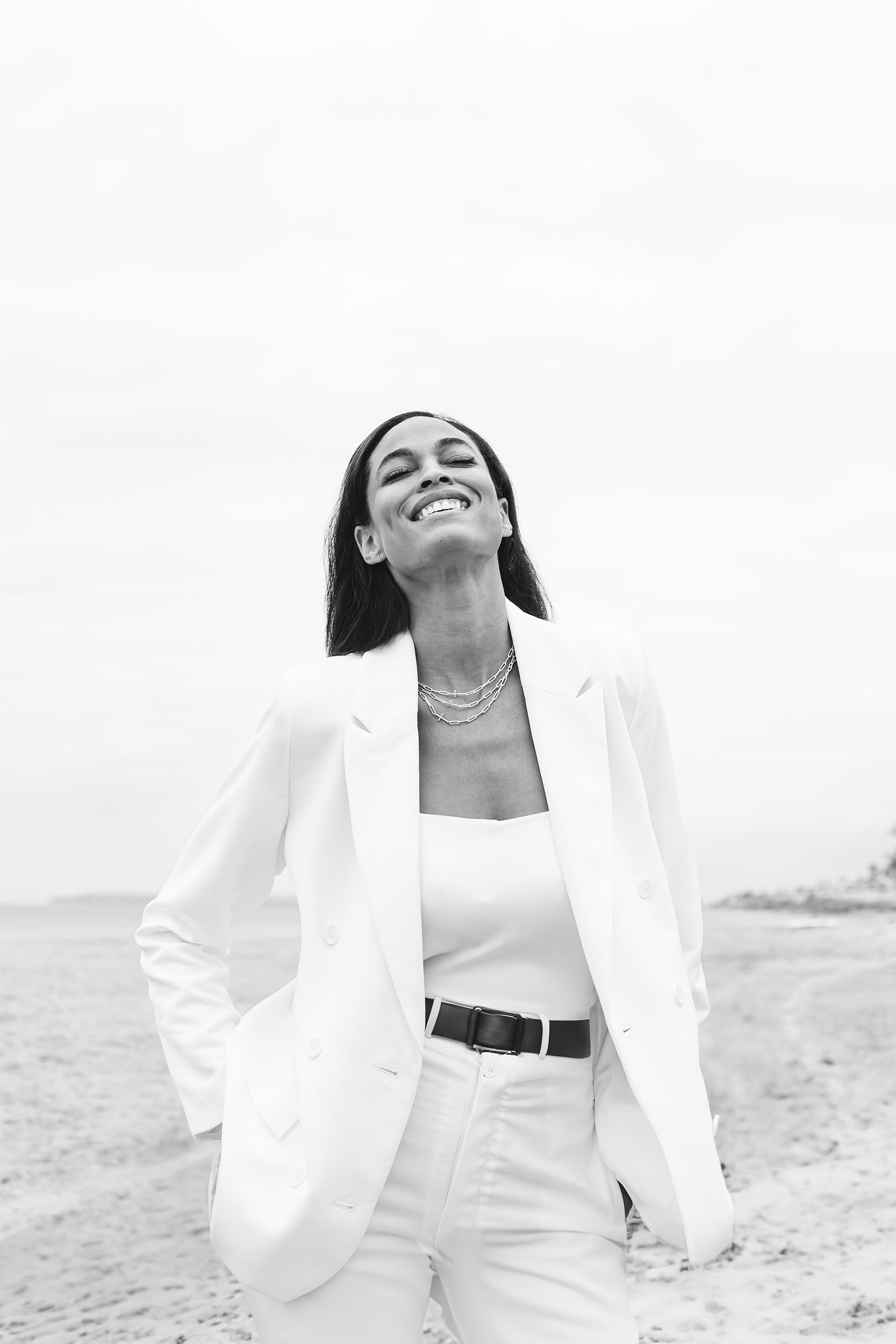 Rizen Jewelry model wearing white suit and 3 chain breaker necklaces featuring a cross pendant on a paperclip chain.
