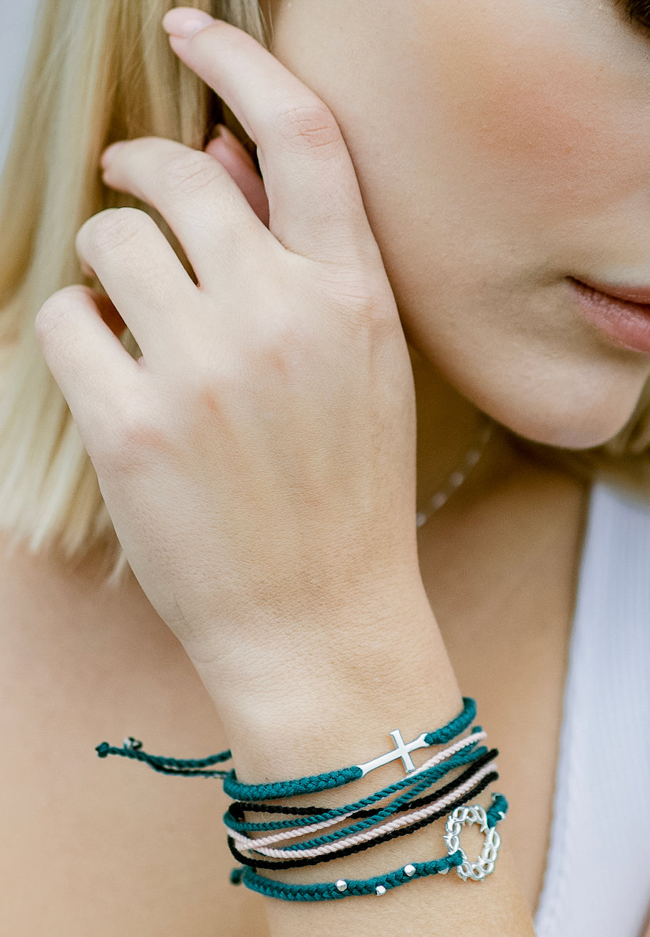 Christian model wearing be magnified joyful friendship bracelet layered with cross and crown of thorns beaded bracelets in azure blue by Rizen Jewelry Made 4 Ministries line. 
